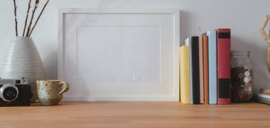 Ahşap masa üzerindeki çerçeve ve ofis malzemeleriyle modern iş yerinin yakın görüntüsü 