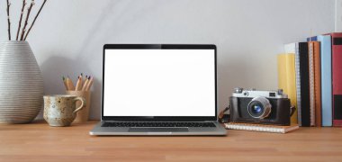 Boş ekran dizüstü bilgisayarı ve ahşap masada ofis malzemeleri olan rahat bir iş yeri. 