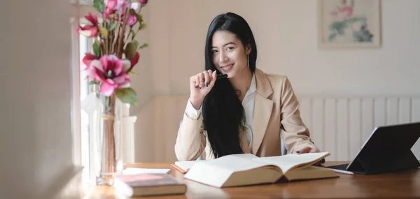 Schöne asiatische Geschäftsfrau arbeitet an ihrem Projekt und lächelt in die Kamera — Stockfoto