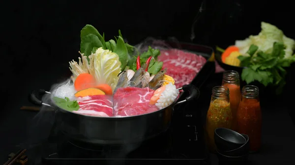 Vista de cerca del shabu shabu en olla caliente con fondo negro, carne fresca en rodajas, mariscos y verduras, estilo japonés de olla caliente — Foto de Stock