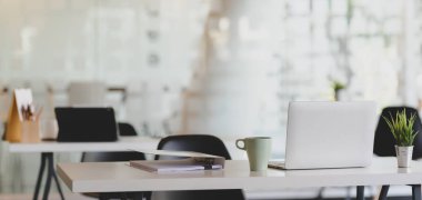 Laptop bilgisayar ve ofis malzemeleriyle ahşap masada rahat bir iş yeri görüntüsü. 