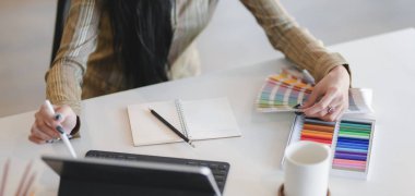 Tasarımcının modern iş yerinde dijital tabletle yaptığı çalışmanın kırpılmış görüntüsü 