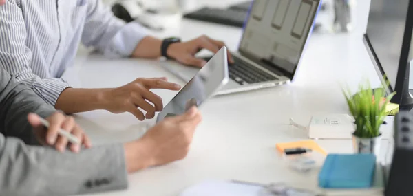 Young professional UI web developer working on his project with laptop computer and tablet in modern workplace