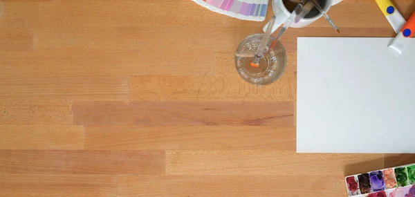 木のテーブルを背景に紙と水の色でアーティストの職場のトップビュー — ストック写真