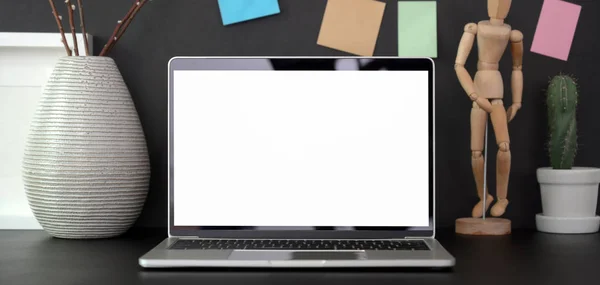 Közelkép a modern munkahely üres képernyős laptop számítógép, irodai kellékek és ragacsos megjegyzés fekete asztal fekete fal háttér — Stock Fotó