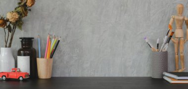 Siyah masa ve gri duvar arka planında ofis malzemeleri ve fotokopi alanı olan moda bir iş yeri