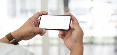 Bulanık ofis geçmişine sahip boş ekran akıllı telefonunu kullanan işadamının yakın görüntüsü 
