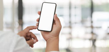 Bulanık ofis geçmişine sahip beyaz ekran akıllı telefonunu kullanarak iş adamının kırpılmış görüntüsü. 