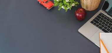 Koyu masa arkasında dizüstü bilgisayarı ve ofis malzemeleriyle trend iş yeri manzarası