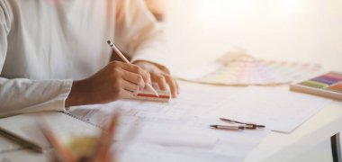Modern ofis odasındaki inşaat planları üzerinde çalışan genç profesyonel mimarın yakın çekimi 
