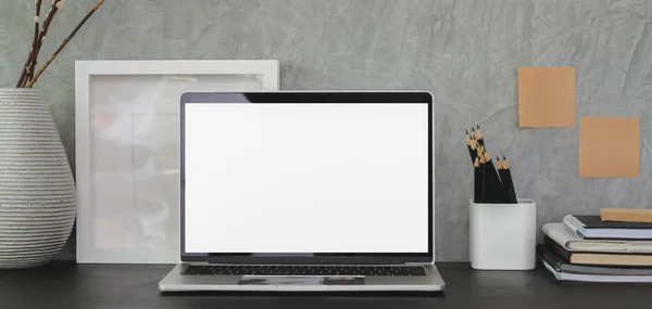 Moderne arbeidsplass med åpen, blank PC med kontorrekvisita på svart bord og grå veggbakgrunn – stockfoto