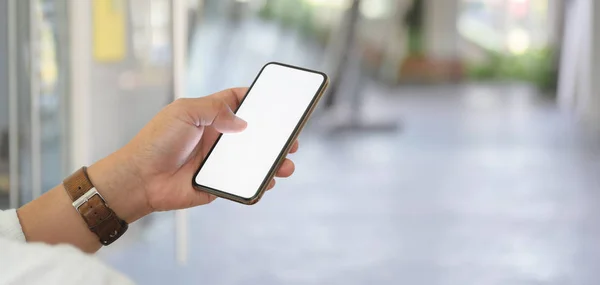 Närbild av affärsman som håller blank skärm smartphone med suddig kontor bakgrund — Stockfoto