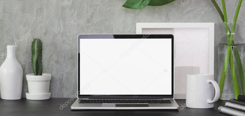 Close-up view of modern office room with blank screen laptop computer and office supplies on black table