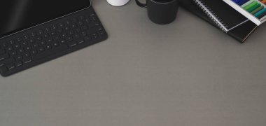 Laptop bilgisayarı ve ofis malzemeleri koyu gri masa arkasında modern iş yeri manzarası