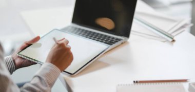 Profesyonel mimarın dijital tabletle inşaat planı üzerinde çalışırken çekilmiş görüntüleri. 