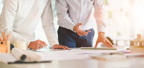 Close-up view of young professional architect and engineer working together on construction plans in modern office room — Stock Photo, Image