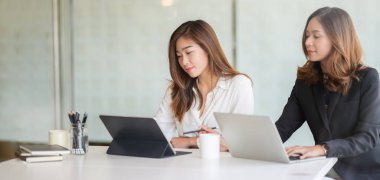 Modern ofis odasında birlikte çalışan iki profesyonel iş kadınının portresi. 