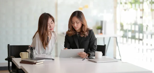Două tinere femei de afaceri care lucrează împreună la strategia lor în timp ce folosesc tabletă — Fotografie, imagine de stoc