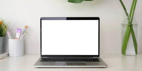 Przycięte ujęcie nowoczesnego miejsca pracy z otwartym pustym ekranem laptopa i materiałów biurowych na białym stole — Zdjęcie stockowe