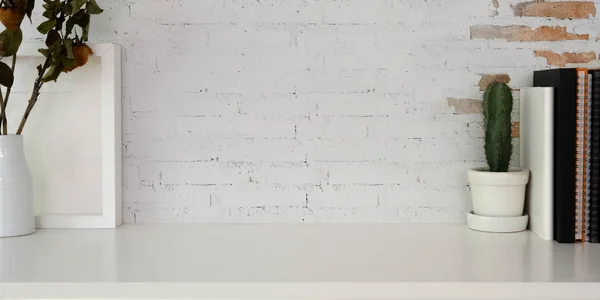 Beskuren bild av modern arbetsplats med mockup ram, kontorsmaterial och kopiera utrymme på vitt bord och tegelvägg bakgrund — Stockfoto