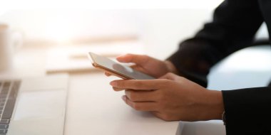 Ofis odasında boş akıllı telefonla çalışan genç bir iş kadınının görüntüsü. 