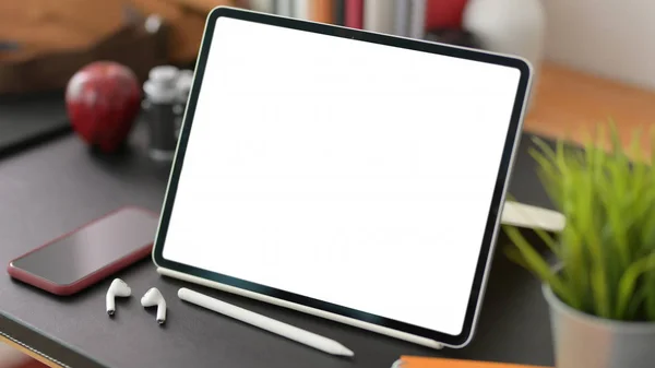 Gehakte opname van stijlvolle werkplek met blanco scherm digitale tablet en kantoorbenodigdheden op zwarte tafel achtergrond — Stockfoto