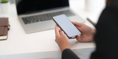 Çalışırken boş ekran akıllı telefonu tutan genç profesyonel iş kadınının yakın plan görüntüsü 