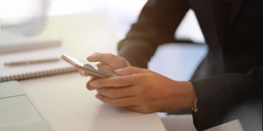 Ofisinde akıllı telefon tutan genç bir iş kadınının görüntüsü. 