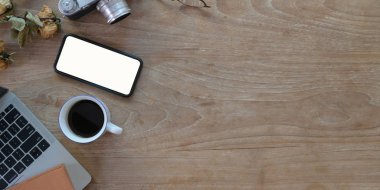 Akıllı telefon, ofis gereçleri ve ahşap masa üzerindeki kopyalama alanının bulunduğu en iyi çalışma alanı manzarası. 