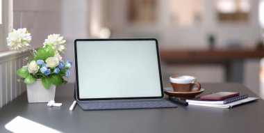 Siyah masa zemininde boş ekran dijital tableti ve ofis malzemeleriyle koyu renkli ve şık iş yerinin yakın görüntüsü 