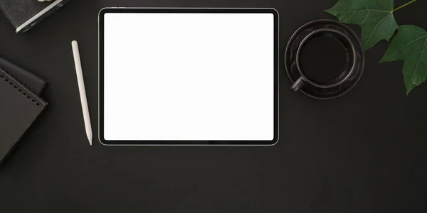 Vista superior del lugar de trabajo moderno con pantalla en blanco tableta digital y taza de café negro sobre fondo de mesa oscura —  Fotos de Stock