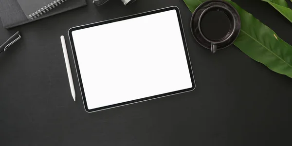 Vista superior del lugar de trabajo moderno oscuro con la tableta digital de la pantalla en blanco con los suministros de oficina en fondo negro de la tabla —  Fotos de Stock