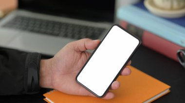 Projesi üzerinde çalışırken boş ekran akıllı telefonu kullanan genç işadamının yakın plan görüntüsü 