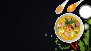 Tavuğun yeşil köri ve siyah masa arkasındaki malzemelerin üst görüntüsü, kopyalama alanı olan Tayland mutfağı konsepti.