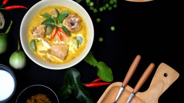 Tavuğun yeşil köri ve siyah masa arkasındaki malzemelerin üst görüntüsü, kopyalama alanı olan Tayland mutfağı konsepti.