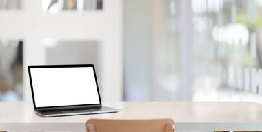 Boş beyaz ahşap masadaki bulanık ofis arka planına sahip boş dizüstü bilgisayarı olan modern işyeri 