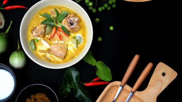 Tavuğun yeşil köri ve siyah masa arkasındaki malzemelerin üst görüntüsü, kopyalama alanı olan Tayland mutfağı konsepti.