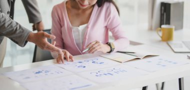 Genç profesyonel iş ekibinin ofis odasındaki belge ve çizelgelerle projeye beyin fırtınası yaptığı yakın plan görüntüsü 