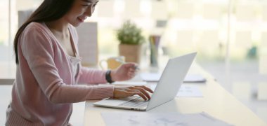 Ofis odasında dizüstü bilgisayarla projesinde çalışan genç iş kadınının yakın plan görüntüsü 