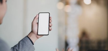 Ofis geçmişi bulanık, elinde boş ekran akıllı telefonu olan profesyonel bir iş adamının görüntüsü. 