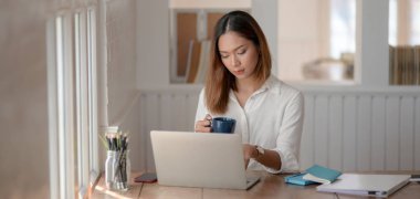 Genç profesyonel iş kadını rahat bir iş yerinde dizüstü bilgisayar kullanırken projesinde çalışıyor.