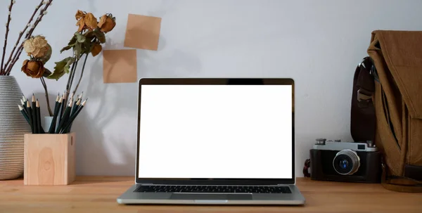 Обрезанный снимок кабинета фотографа с чистым экраном ноутбука, офисных принадлежностей и камеры — стоковое фото