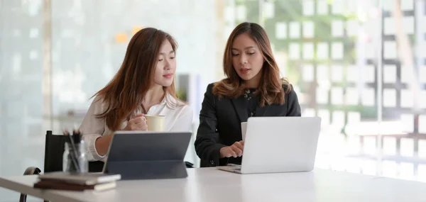 Twee jonge professionele zakenvrouwen die samen het projectplan bekijken in een moderne kantoorruimte — Stockfoto