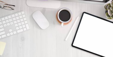 Boş ekran tableti, ofis malzemeleri ve beyaz ahşap masa arka planında kopyalama alanı olan rahat bir iş yeri görüntüsü. 