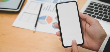 Ofiste boş ekran akıllı telefon kullanırken genç işadamının projesi üzerinde çalışırken çekilmiş görüntüleri. 