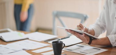 Ofis odasında tabletle projesinde çalışan genç profesyonel ux web tasarımcısının yakın plan görüntüsü 
