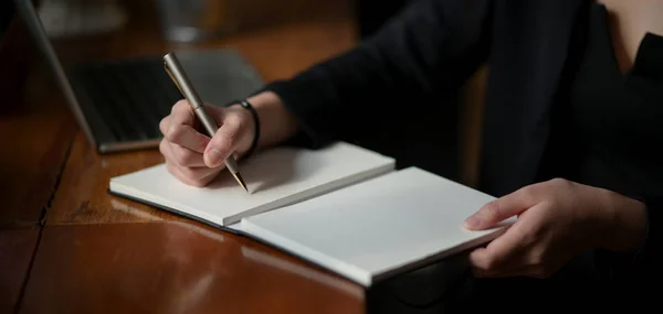 Cropped shot of young professional businesswoman analysing the concept on notebook in modern office room — ストック写真