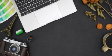 Dizüstü bilgisayarı ve ofis malzemeleri siyah masa arkasında modern tasarımcı ofis odasının üst görüntüsü 