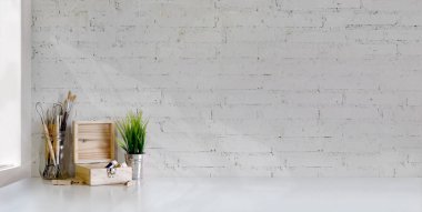 Beyaz masa ve beyaz tuğla duvar arkaplan boyama araçları ile minimal sanatçı iş yeri kırpma 