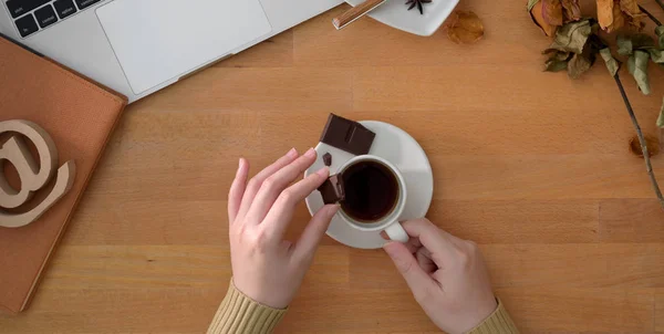 Top view of woman holding coffee cup in comfortable workplace with office supplies on wooden table — Stock Photo, Image